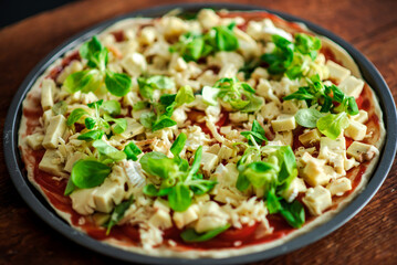 Pizza with lots of cheese and herbs. Cheesy pizza in a round shape on a wooden background.