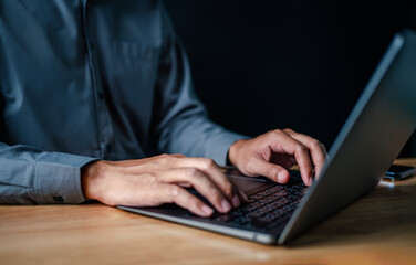 laptop, typing, close up, hand, businessman, portrait, background, blue, keyboard, formal. picture is portrait close up to businessman, him typing at keyboard on laptop in a serious way for something.
