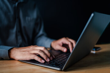 laptop, typing, close up, hand, businessman, portrait, background, blue, keyboard, formal. picture is portrait close up to businessman, him typing at keyboard on laptop in a serious way for something.
