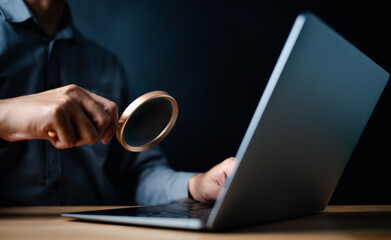 laptop, typing, close up, hand, businessman, portrait, background, blue, keyboard, formal. picture is portrait close up to businessman, him typing keyboard and another hand hold magnifier for finding