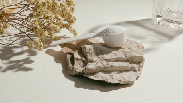 Sport supplement, creatine, hmb, bcaa, amino acid or vitamin measure with powder in a lifestyle contest. 4k high quality video. Sport nutrition health and food concept. Dry flowers, stones and shadows