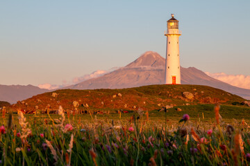 Stunning sunset view of Cape Egmont Lighthouse in front of Mt Taranaki on New Zealand's North Island