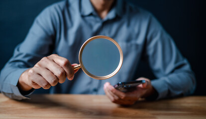Fototapeta na wymiar smartphone, magnifier, close up, hand, businessman, portrait, background, blue, play, formal. picture is close up to businessman, him hold smart phone and another hand hold magnifier for finding.