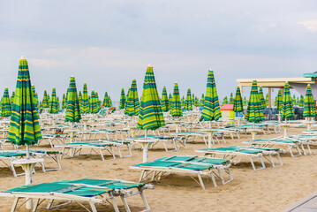 In the morning, by the sea, empty sun loungers, chairs and locked umbrellas on the beach.