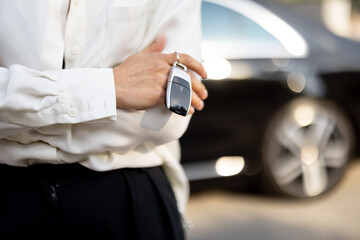 Business woman holds a keychain of a luxury car outdoors, close-up. Concept of business transfer service and transportation