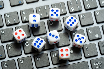 A set of simple small game dice showing different numbers laying on a laptop computer keyboard, random numbers generation, chance, luck, drawing. Randomness, online lottery gambling chances, entropy - obrazy, fototapety, plakaty
