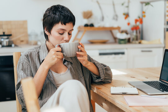 Woman sitting in the kitchen drinking coffee.
