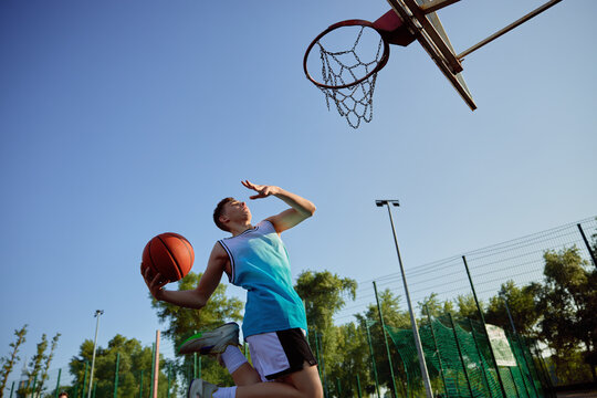 Teenager aiming into basketball hoop playing on playground