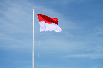 Indonesian flag with blue sky background, waving red and white flag