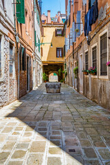 Fototapeta na wymiar Narrow pedestrian cabblestone old alleys in Venice, Italy. Old worn out medieval buildings.