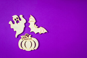 Wooden toy bat, ghost, pumpkin on purple background Halloween concept