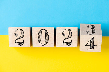 2024 Happy new year concept. Flipping of wooden cube block change from 2023 to 2024 on yellow and...