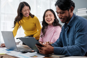 Group of young Asian business people brainstorming, looking at laptop computer.