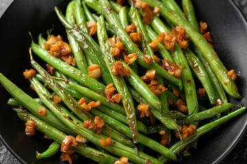 Stir fried garlic, ginger green beans in black bowl