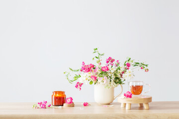 summer flowers, burning candles and cup of tea   on light background