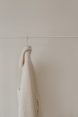 Autumn outerwear on hanger over white wall. Warm white jacket. Aesthetic wardrobe with clothes in neutral colours