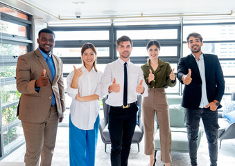 Fototapeta premium Portrait group of multiethnic business men and women stand in the office and show thumbs up to the camera with smiling.