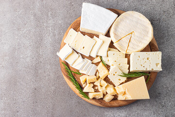 Wooden board with various cheese and olives. Brie. Camembert. Parmesan, feta, blue cheese. Italian, French cheese.