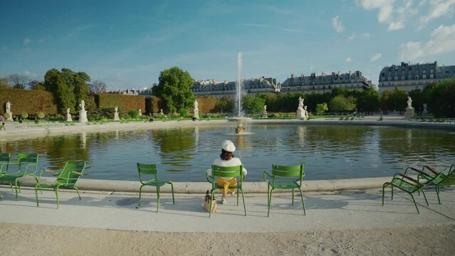 Young tourist woman on a chair in Tuileries park in Paris