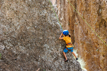 climber boy. a child in a helmet climbs a rock using equipment. children's sports.