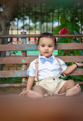 isolated cute toddler with innocent facial expression sitting at rusty iron bench at outdoor