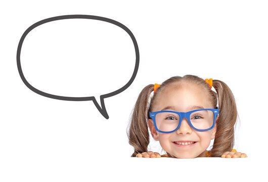 Beautiful cute little girl hiding under a table and smiling to the camera while a blank speech balloon standing on the left on white background.