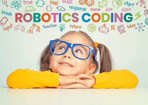 Beautiful cute little girl with eyeglasses looking at colorful Robotics Coding text symbols and commands above her head.  Kid programmer learning coding. Programming languages concept.  