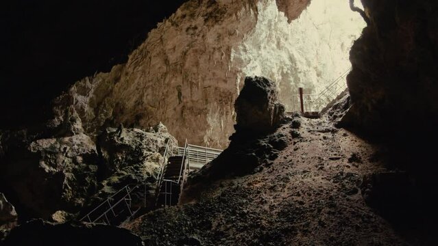 The entrance to the cave with wooden pathway, stairs and breathtaking formations, stalactites, and stalagmites that adorn the cavern walls flooded with sunlight in Mammoth Cave, Margaret River