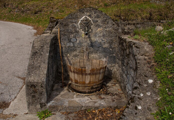 An old historic stone drinking water fountain in the village of Trava in Lauco district, Udine...
