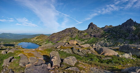 Russia. South of Siberia. Western Sayan. Panoramic view of a high-altitude lake surrounded by harsh rocks from a mountain pass in the Ergaki Natural Mountain Park.
