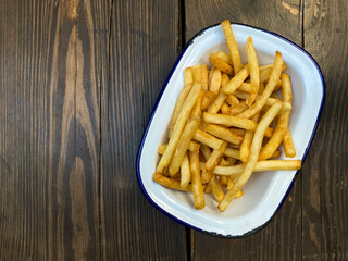 French fries on a plate on a wooden background. Fast food. Top view, copy space. 