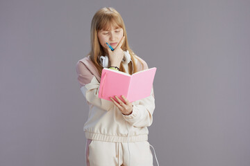 pensive modern pupil in beige tracksuit with workbooks