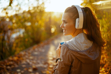 smiling elegant woman in park listening to music