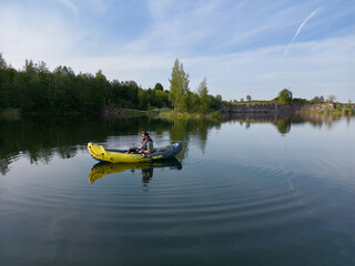 The guy floats on an inflatable boat on the lake on a summer morning.