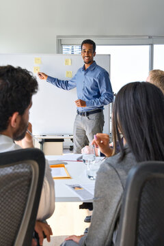 African Business Man Presenter Team Leader Giving Presentation Training On Whiteboard In Office. Company Executive Manager Presenting Corporate Strategy At Group Conference Workshop Meeting. Vertical