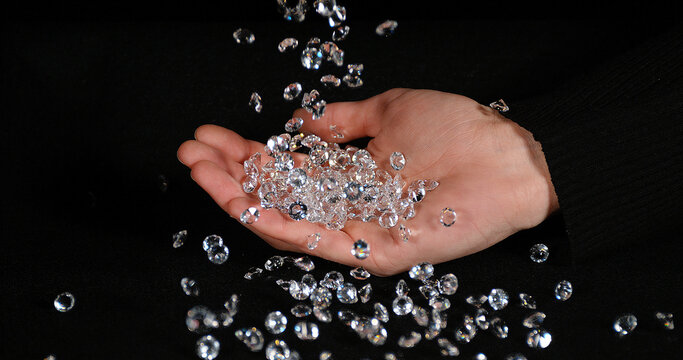 Diamonds falling into Hand against Black Background