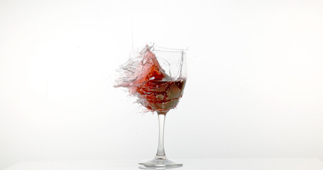 Glass of Red Wine Breaking and Splashing against White Background