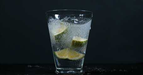 Green Citrus, citrus aurantifolia, falling into a Glass of Water,