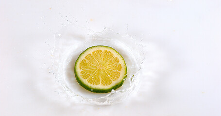 Green Lemons, citrus aurantifolia , Fruits falling on Water against White Background