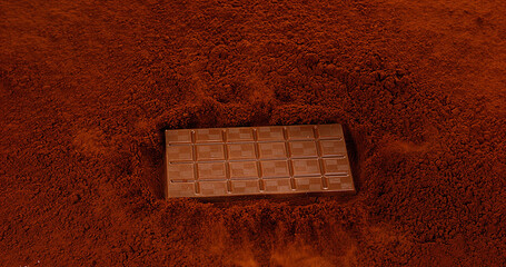 Milk Chocolate Tablet falling on Black Chocolate Powder