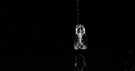 Glass of Water Bouncing and Splashing on Black Background