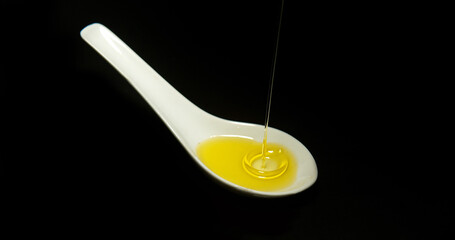 Olive Oil, Falling in a Spoon against Black Background