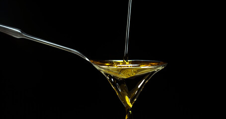 Olive Oil, Falling in a Spoon against Black Background