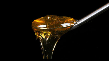 Honey Flowing from Spoon against Black Background