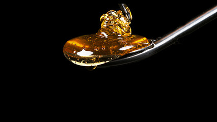 Honey Flowing from Spoon against Black Background