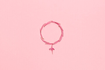 Female gender symbol made with pink flower petals on pink abstract background. Woman medicine and...