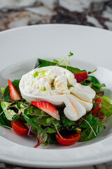 Diet food salad with burata cheese, strawberries, cherry tomatoes, spinach, beet leaves, lettuce and balsamic sauce.