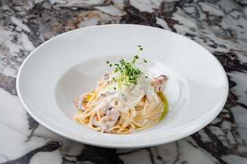 Lunch pasta with bacon, cream sauce and microgreens in a plate.