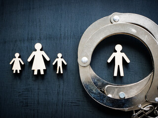 Family figurines and handcuffs as concept of domestic violence.