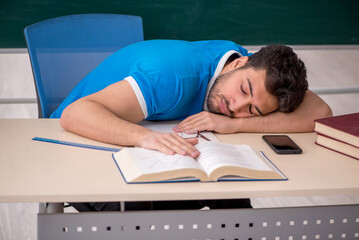 Young male teacher student in front of green board